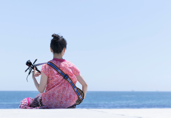 海を眺めて三線を弾く女性,沖縄